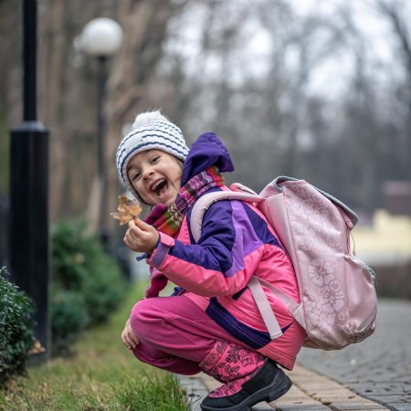 little-girl-looks-leaves-outside-cold-season-min