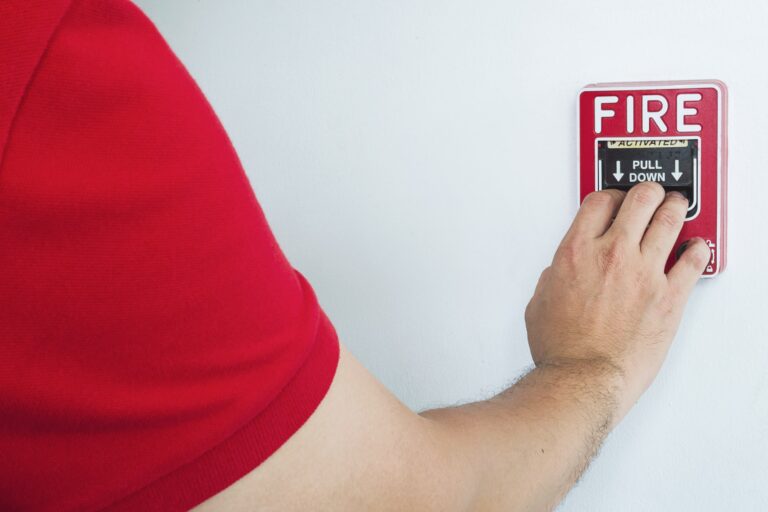 man-is-reaching-his-hand-push-fire-alarm-hand-station-min